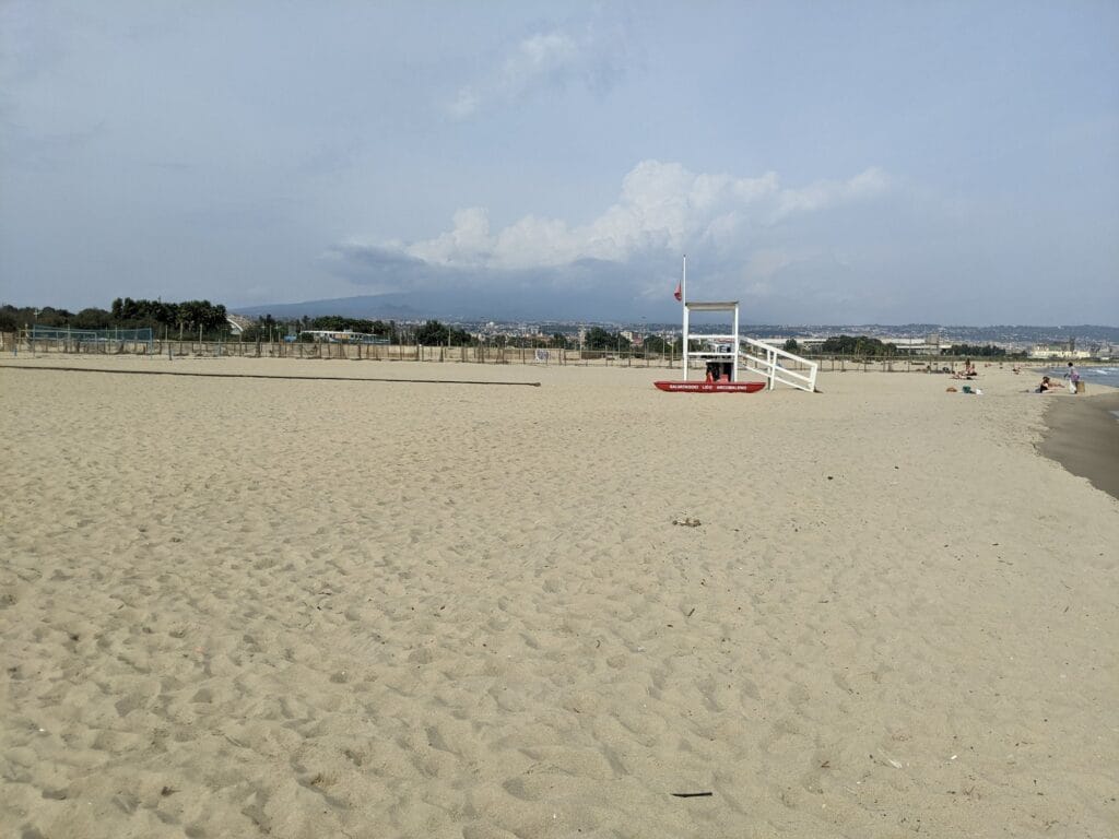 Szeroka piaszczysta plaża na południe od Katanii z wieżą ratownika
